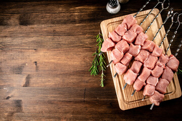 Pork kebab raw on skewers on a cutting board. 
