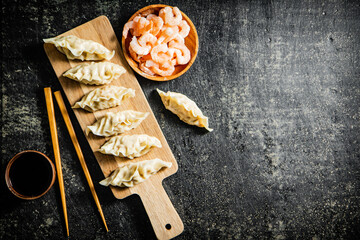Dumplings gyoza with shrimp on a wooden cutting board with soy sauce. 