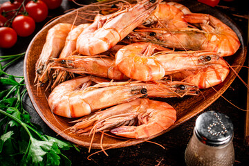Boiled shrimp on a plate with tomatoes and parsley. 