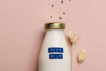 sesame seed milk in bottle on beige background with plant. copy space. Raw diet meal. Healthy...
