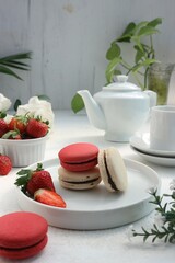 red and white macarons with fresh strawberries, flowers and a white pot
