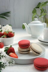 red and white macarons with fresh strawberries and a pitcher of white