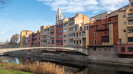 Fototapeta na wymiar Colorful houses reflected in the Onyar river, in Girona, Catalonia, Spain. Church of Sant Feliu and Cathedral of Santa María in the background