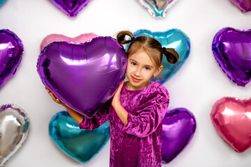 A cute lovely lady is holding a purple foil balloon in the shape of a heart, congratulating on Valentine's Day.