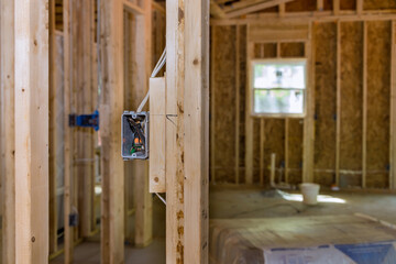 An unfinished wood frame house with basic electrical wiring is being constructed on new residential construction site