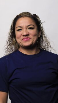 Video of a Mexican woman holding mobile phone and dancing happy, smiling, looking to the camera isolated over white background
