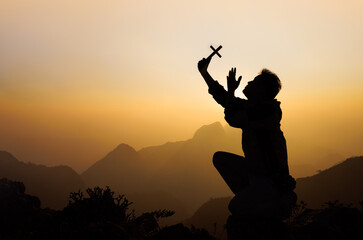 Silhouette of a man praying on the mountain at sunrise, beautiful landscape, spirituality and religion,man praying to god. Christianity concept.