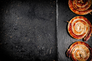 Round grilled sausages on a black background.