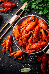 Boiled crayfish in a colander on a stone board. 