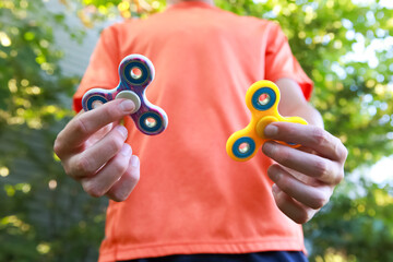 Teen boy with a fidget spinner sensory toys outdoors