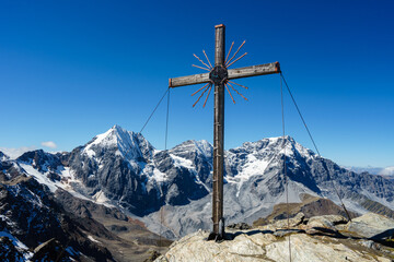 Summit cross on the Madritschspitze in South Tyrol, Italy, with the Ortler and the Königsspitze in...