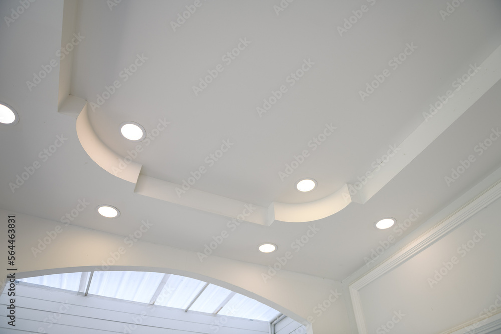 Poster stretch ceiling white and complex shape. ceiling with halogen spots lamps and drywall construction i