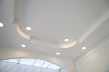 Stretch ceiling white and complex shape. ceiling with halogen spots lamps and drywall construction...