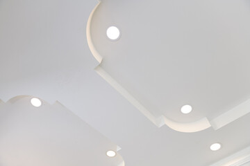 Stretch ceiling white and complex shape. ceiling with halogen spots lamps and drywall construction in empty room in exhibition hall or house.