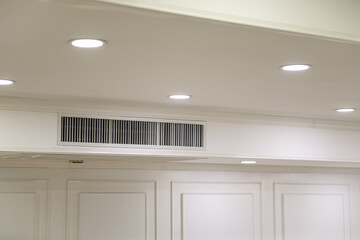 Ceiling mounted cassette type air conditioner and modern lamp light on white ceiling. duct air...