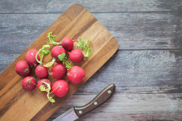 Fresh red radish bundle on chopping board on table 