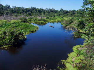 Fototapeta na wymiar Aerial View of canoe boat in the middle of the Amazon River with lush tropical rainforest vegetation 