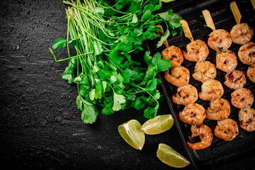 Grilled shrimp in a frying pan with parsley and pieces of lime. 