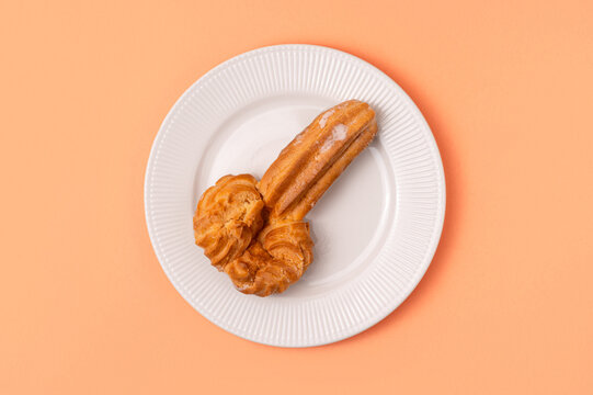Traditional portuguese pastry in the shape of penis on white plate on beige background