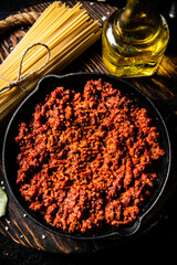 Bolognese sauce in a frying pan with a bunch of pasta dry. 