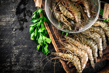 Raw shrimp in a colander and on a cutting board. 