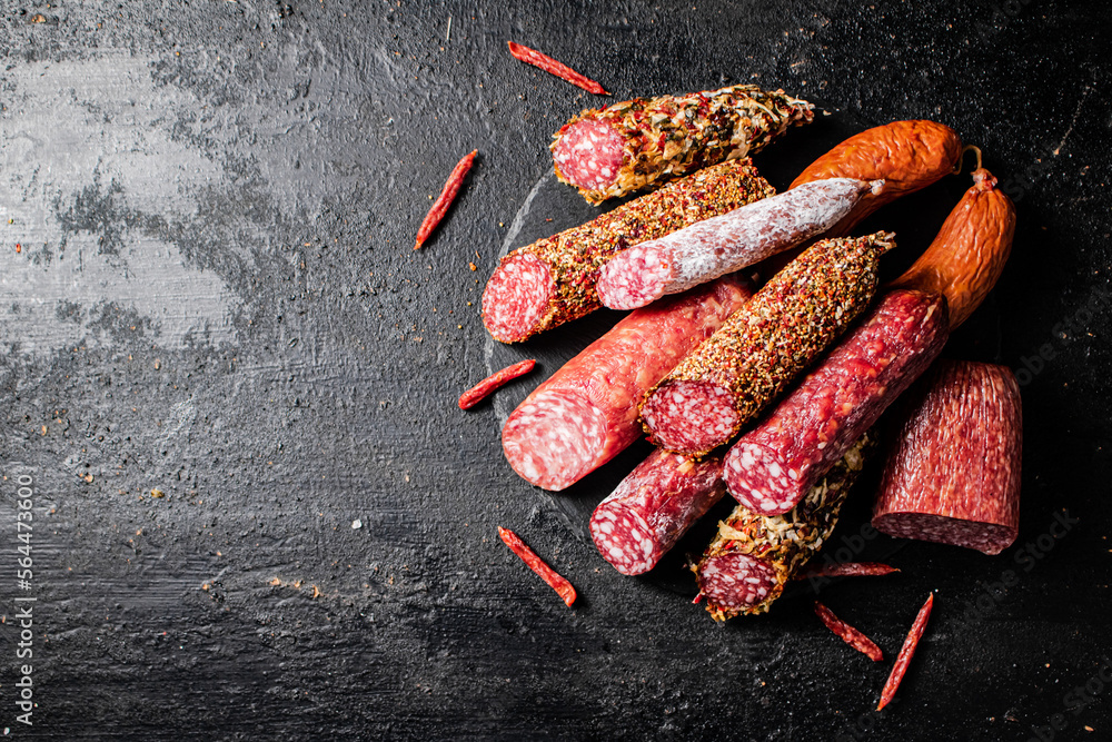 Wall mural A variety of types of salami sausage with dried chili peppers on the table. 