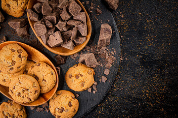 Cookies with pieces of milk chocolate on a stone board. 