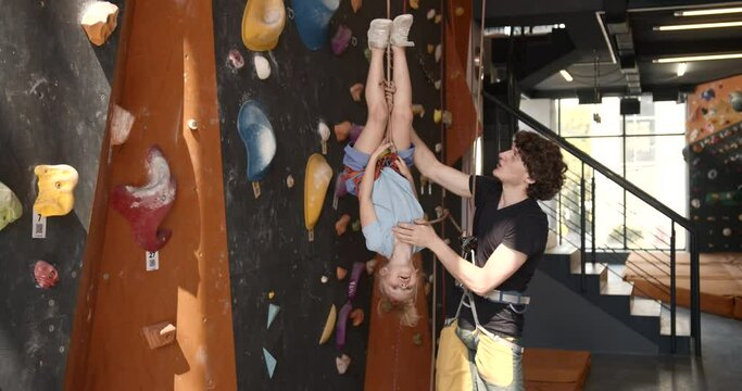 Male trainer assisting a girl in rock climbing