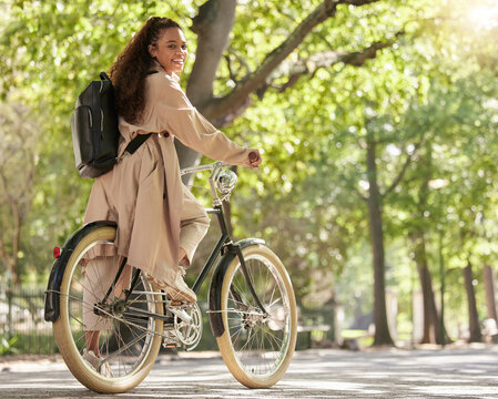 Bicycle, bike and woman travel in a park outdoors in nature happy and excited on fun ride or commuting. Exercise, wellness and lifestyle female student cycling and relaxing on eco friendly traveling