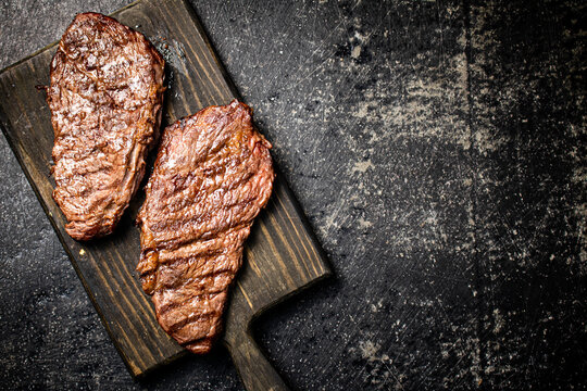 Grill steak on a wooden cutting board.