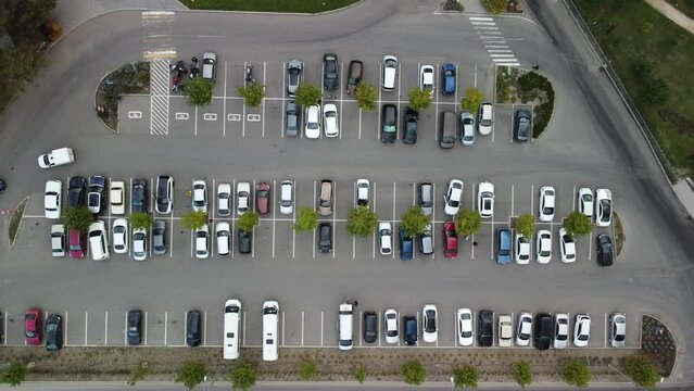 Busy large modern carpark with symmetrical roads rows of parking bays lots of symmetry and colours aerial view from drone up above looking down.