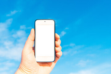 Mockup image of hand holding white mobile phone with blank white screen in blue sky white cloud background.Copy space.