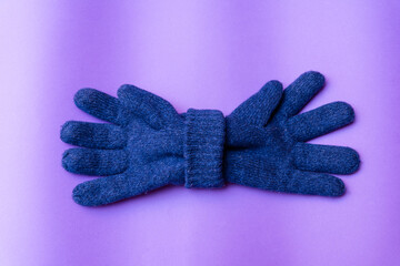 April fools day concept.A Pair of Knitted blue Gloves on purple Background.