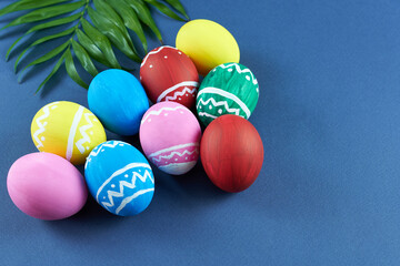 Colorful Easter eggs on a blue background with a green twig. Bright background of Easter eggs. 