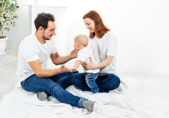 mom and dad sit on the floor and play with the baby. a happy family. family in studio or at home