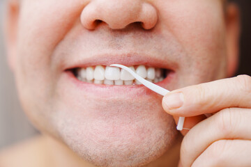 Naklejka premium a man's mouth close-up. a man brush your teeth plastic toothpick with dental floss. concept of hygiene and health of teeth and oral cavity. daily care and brushing of teeth.