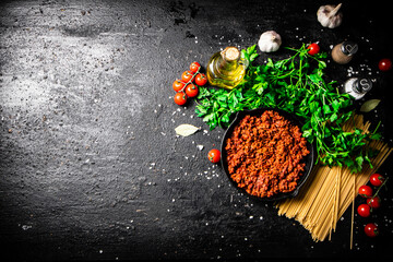 Obraz na płótnie Canvas Bolognese sauce in a frying pan with pasta dry and parsley. 