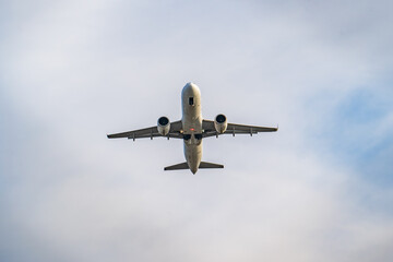 Fototapeta na wymiar Passenger plane flies in sky, view from below. Airplane travel concept.