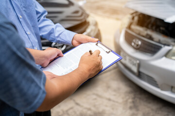 Insurance officer writing Insurance Claim Report on clipboard while insurance. Man and Insurance agent claim process after car crash
