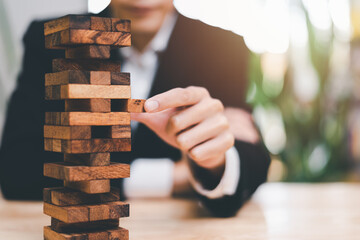 Businessman pulling a jenga wooden box,financial risk management and strategic planning,through...