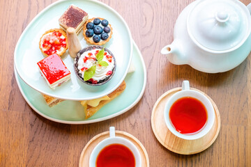 Top view of sweet delights with afternoon tea stand, teapot and tea cups