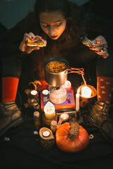 Close up woman witch brewing medicine in cauldron portrait picture. Herbal tea mixture. Closeup top...