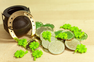 Saint Patrick's Day. Green petal clovers and little pot with gold leprechaun coins on wood...