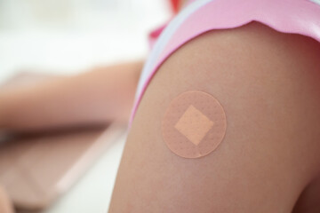 Vaccinated little asian girl with adhesive plaster after vaccine injection
