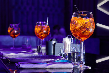 Alcoholic cocktails with ice and a pieces of orange on the served table of the nightclub