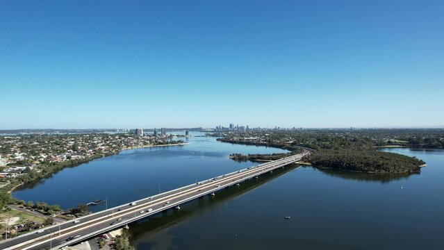 Aerial view of cars driving across the Mount Henry freeway bridge with the Perth city skyline in the distance.
