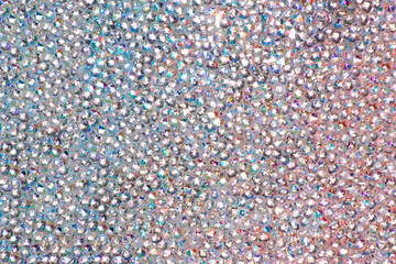 Abstract rhinestones background. Texture of rhinestones illuminated with multi-colored light. Pink and blue shine diamonds. Close up. Flares on glass - obrazy, fototapety, plakaty