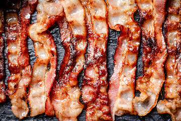 Strips of fried bacon on a black background.