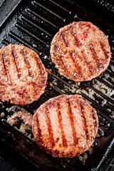 Cooking a delicious grilled burger on a pan with oil bubbles.