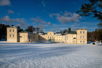 State Classicist chateau Kynzvart in winter under snow and with blue sky - castle is located near the famous west Bohemian spa town Marianske Lazne (Marienbad) - Czech Republic